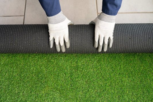 two hands rolling artificial grass on a patio